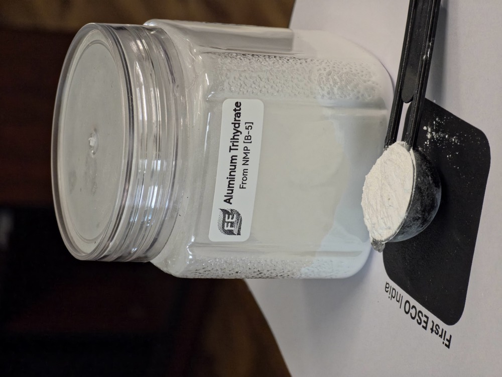 NMP waste jar beside the aluminium trihydrate recovered from it, on the lab bench
