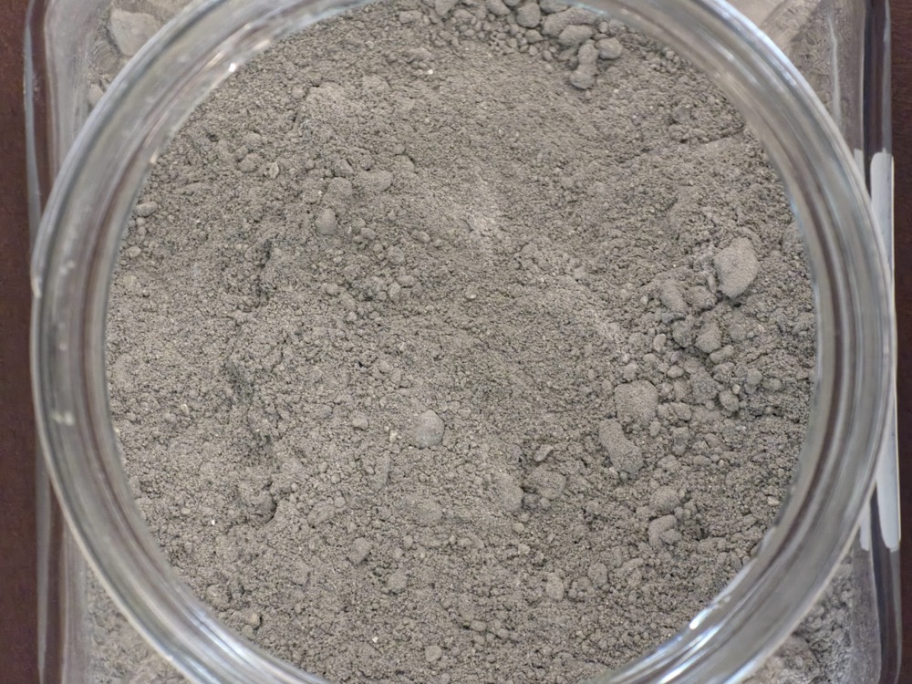 NMP waste sample: grey metallic sludge in a jar