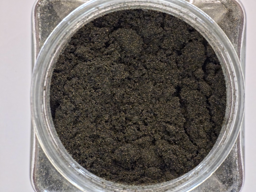 Titanium ETP waste sample: dark granular sludge in a jar